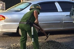 Cảnh sát mua đá dăm lấp ổ gà giữa đường