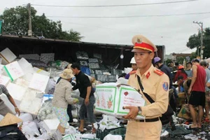 Xe tải lật, CSGT cùng dân giúp gom hàng