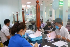 Cán bộ tiếp dân và người dân đến TTHC công TP Thủ Dầu Một đều đeo khẩu trang. Ảnh: LÊ ÁNH