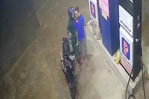Kẻ cướp kề liềm vào cổ, cướp tiền của nhân viên cây xăng. Ảnh chụp màn hình