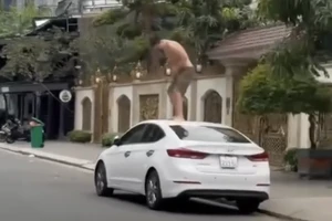 Người đàn ông đứng trên nóc ô tô đập phá. Ảnh: TN