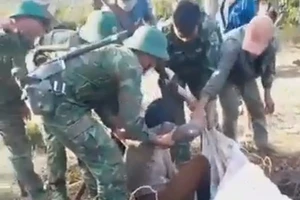 Người phụ nữ tay cầm con rắn khi lực lượng cứu hộ đưa lên khỏi giếng hoang