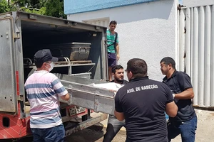 Nhân viên pháp y khiêng thi thể nạn nhân thiệt mạng ra xe. Ảnh: REUTERS