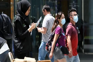 Một tình nguyên viên của Bộ Truyền thông Singapore thu thập phản hồi của người dân về tình hình dịch Corona. Ảnh: AFP