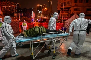 Nhân viên y tế đang đưa một bệnh nhân Corona đến bệnh viện ở Vũ Hán ngày 8-2. Ảnh: AFP