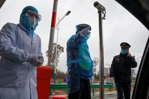 Một nhân viên y tế và hai cảnh sát tại một chốt kiểm dịch trên đường phố Vũ Hán (Ảnh chụp ngày 10-2). Ảnh: AP