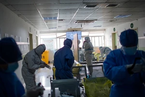 Nhân viên y tế đang tiến hành mặc đồ bảo hộ y tế trước khi bước vào khu vực cách ly ở Hồ Bắc ngày 22-2. Ảnh: AFP