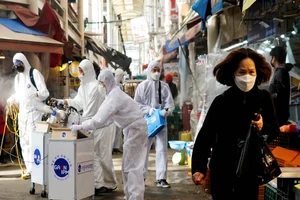 Một người phụ nữ đeo khẩu trang khi nhân viên của một y tế khử trùng một khu chợ truyền thống ở thành phố Seoul, Hàn Quốc. Ảnh: REUTERS 