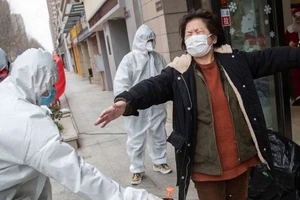 Xịt khử trùng một phụ nữ vừa được xuất viện sau khi điều trị thành công tại Vũ Hán ngày 1-3. Ảnh: AFP 