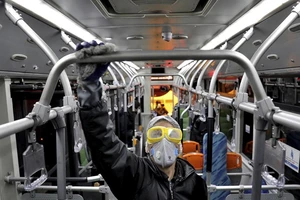 Một nhân viên y tế khử trùng một xe buýt ở thủ đô Tehran (Iran) ngày 28-2. Ảnh: AFP