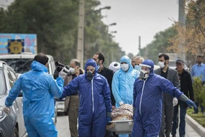 Nhân viên y tế di chuyển môt bệnh nhân tử vong do COVID-19 ở tỉnh Mazandaran (Iran) ngày 7-3. Ảnh: AFP