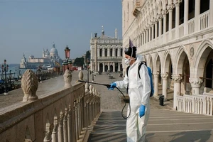 Nhân viên y tế khử trùng tại cầu Ponte della Paglia trên quảng trường Saint Mark ở TP Venice, Ý. Ảnh: REUTERS
