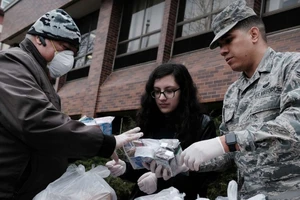 Một quân y Mỹ phát thực phẩm và trang thiết bị y tế cứu trợ cho người vô gia cư ở bang California ngày 14-3. Ảnh: AFP