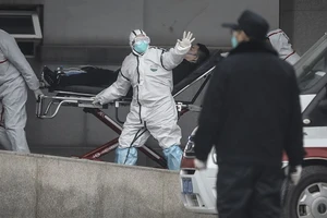 Nhân viên y tế di chuyển một bệnh nhân nhiễm COVID-19 ở Vũ Hán, Trung Quốc (Ảnh chụp ngày 17-1). Ảnh: AFP