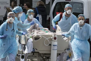 Nhân viên y tế di chuyển bệnh nhân nhiễm COVID-19 ở thủ đô Milan, Ý ngày 12-3. Ảnh: REUTERS