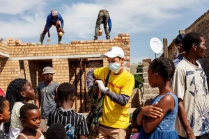 Một tình nguyện viên phát xà phòng cho những đứa trẻ ở TP Johannesburg, Nam Phi. Ảnh: AFP