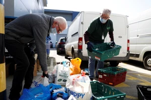 Tình nguyện viên sắp xếp thực phẩm cứu trợ cho người thu nhập thấp ở quận Enfield, Anh ngày 25-3. Ảnh: REUTERS