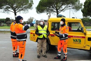 Nhân viên tình nguyện đi phát khẩu trang miễn phí ngừa COVID-19 ở TP Grosseto, vùng Tuscany (Ý). Ảnh: REUTERS