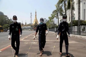 Các nhân viên khử trùng đường phố ở TP Yangon, Myanmar ngày 30-3. Ảnh: AFP