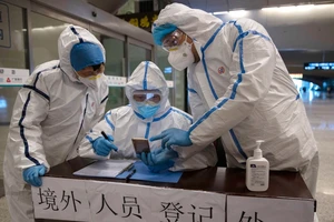 Nhân viên y tế kiểm tra lịch sử đi lại của hành khách tại một nhà ga ở TP Vũ Hán, Trung Quốc ngày 29-3. Ảnh: REUTERS