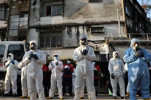 Các nhân viên y tế Malaysia cầu nguyện trước khi tiến hành khử trùng một khu phố ở Kuala Lumpur ngày 1-4. Ảnh: REUTERS