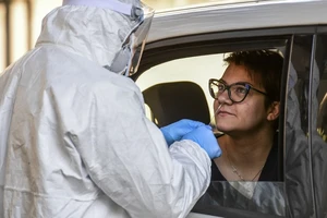 Nhân viên y tế TP Alessandria đang lấy mẫu xét nghiệm COVID-19 cho một phụ nữ tại điểm xét nghiệm lưu động. Ảnh: THE LOCAL