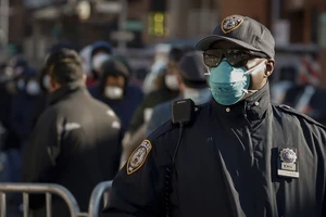 Cảnh sát TP New York (Mỹ) đeo khẩu trang giữ trật tự một đoàn người xếp hàng chờ xét nghiệm COVID-19 ở bệnh viện Elmhurst. Ảnh: REUTERS