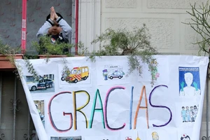 Một em bé ở Barcelona vẽ tranh và vỗ tay cảm ơn các y bác sĩ trên tuyến đầu của cuộc chiến chống COVID-19 ở Tây Ban Nha. Ảnh: REUTERS