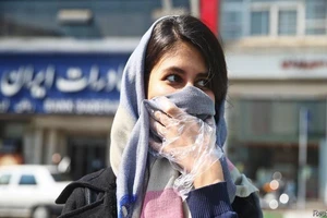 Một cô gái Iran lấy khăn choàng che mặt khi ra đường. Ảnh: REUTERS