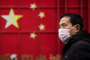 Một người dân đi bên cạnh container sơn màu cờ Trung Quốc tại TP Thâm Quyến ngày 12-3. Ảnh: CNN