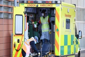 Nhân viên y tế đang khử trùng xe cứu thương tại thủ đô London (Anh). Ảnh: AFP 