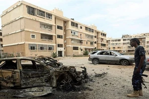 Một binh sĩ thuộc lực lượng chính phủ (GNA) bên cạnh một chiếc ô tô bị phá hủy do đợt bắn phá của lực lượng LNA nhắm vào trung tâm thủ đô Tripoli hôm 9-5. Ảnh: AFP