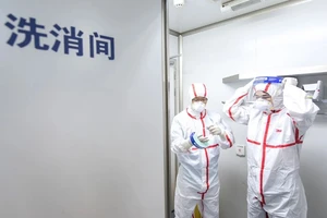 Hai nhà nghiên cứu thực hiện quy trình an toàn trước khi vào làm việc trong phòng thí nghiệm của Viện Virus học Vũ Hán, tỉnh Hồ Bắc, Trung Quốc. Ảnh: TÂN HOA XÃ