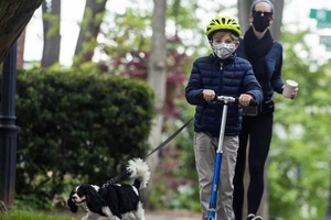 Một cậu bé và mẹ dắt thú cưng đi dạo ở công viên Montrose ở thủ đô Washington D.C. hôm 11-5. Ảnh: REUTERS
