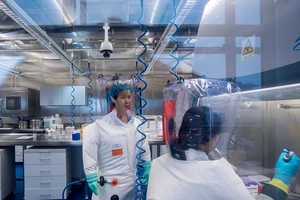 Chuyên gia virus học Thạch Chính Lệ (trái) làm việc trong phòng thí nghiệm an toàn sinh học cấp độ 4 thuộc Viện Virus học Vũ Hán hôm 23-2-2017. Ảnh: AFP