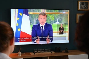 Một gia đình Pháp nghe bài phát biểu của Tổng thống Emmanuel Macron trên kênh truyền hình TFI. Ảnh: AFP