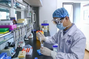 Một nhân viên Sinopharm đang lấy mẫu vaccine ngừa COVID-19 tiềm năng do tập đoàn này phát triển. Ảnh: TÂN HOA XÃ
