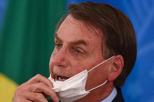 Tổng thống Brazil Jair Bolsonaro tháo khẩu trang tại một cuộc họp báo về COVID-19 vào tháng 3. Ảnh: Andre Borges/AP