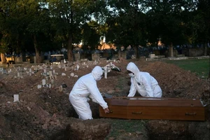 Hai nhân viên đang chôn cất xác của một bệnh nhân tử vong vì virus SARs-CoV-2 tại một nghĩa trang ở Brazil hồi tháng 5. Ảnh: REUTERS/Ricardo Moraes