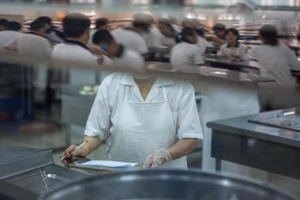 Giáo viên đang chuẩn bị thức ăn cho học sinh. Ảnh: CNN