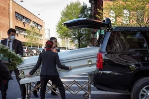 Người dân Mỹ đeo khẩu trang di chuyển một quan tài vào xe tang.