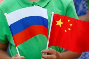 Một đứa trẻ cầm quốc kỳ của Nga và Trung Quốc tại lễ đón Tổng thống Nga Vladimir Putin đến thăm Bắc Kinh, ngày 25-6-2016.