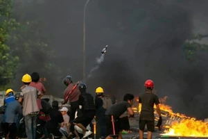 Người biểu tình đứng gần lốp xe đang cháy trong cuộc trấn áp của lực lượng an ninh ở Yangon.