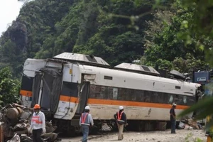 Các nhân viên cứu hộ đang xử lý một toa tàu bị hư hỏng sau vụ tai nạn đâm vào xe tải hôm 2-4.