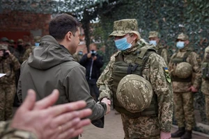 Tổng thống Ukraine Volodymyr Zelensky (trái) bắt tay thăm hỏi một nữ quân nhân trong chuyến thị sát tuyến phòng thủ ở Donbass. Ảnh: AFP