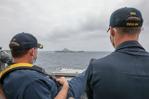 Thuỷ thủ tàu USS Mustin ngồi quan sát tàu sân bay Liêu Ninh của Trung Quốc ngày 5-4. Ảnh: HẢI QUÂN MỸ