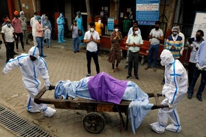 Nhân viên y tế khiêng thi thể nạn nhân COVID-19 trước một lò hoả táng tại New Delhi, Ấn Độ. Ảnh: REUTERS