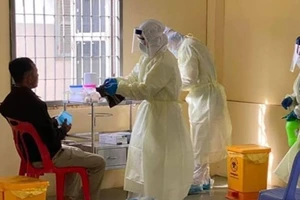 Các nhân viên y tế đang lấy mẫu xét nghiệm COVID-19 của một người đàn ông ở Campuchia.