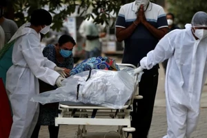 Nhân viên y tế di chuyển một nạn nhân tử vong vì COVID-19 ở TP Ahmedabad, Ấn Độ, ngày 26-4. Ảnh: AP