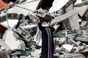 Một phụ nữ đứng khóc gần đống đổ nát của một tòa nhà đã bị phá hủy trong một cuộc không kích của Israel ở Dải Gaza, ngày 16-5.